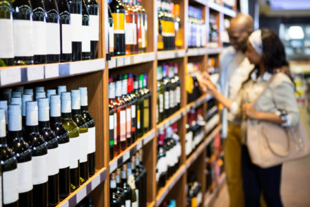 Couple looking at wine bottle in grocery section at supermarket